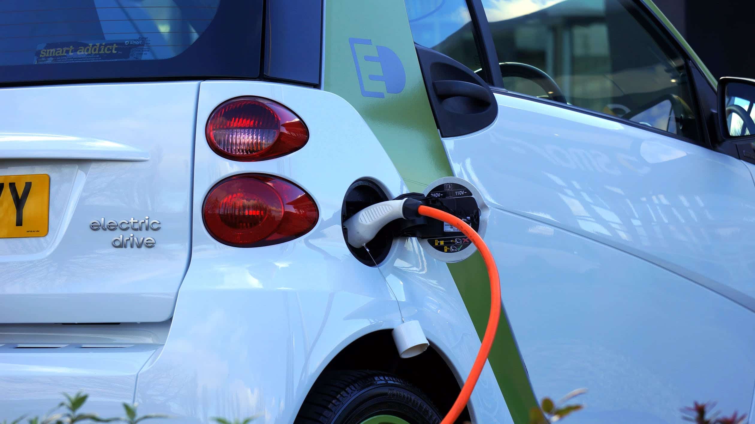 Voiture électrique blanche branchée et en chargement